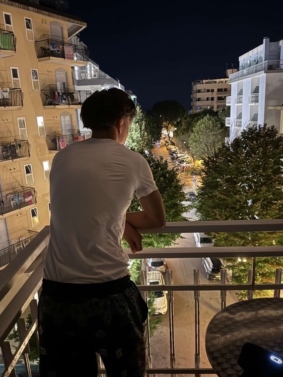 On a balcony at night, looking down a lit street