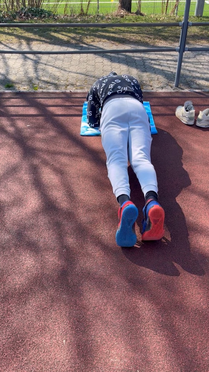 Vinicius holding a plank on a mat on the running track