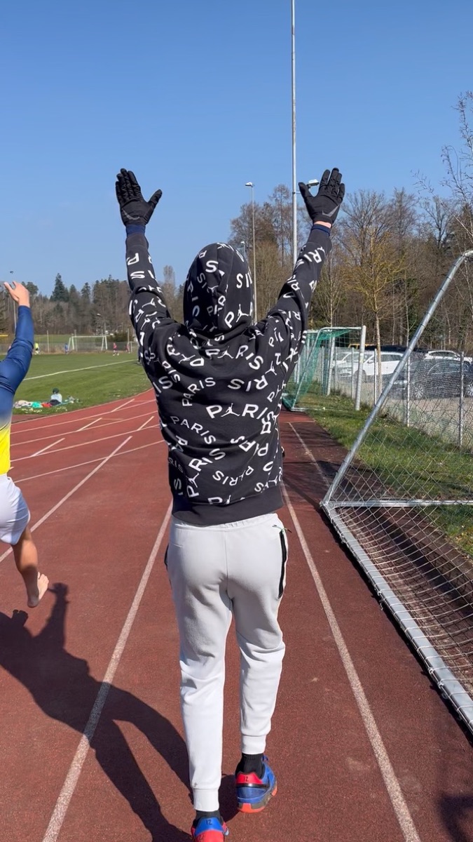 Vinicius walking down the running track with both arms raised